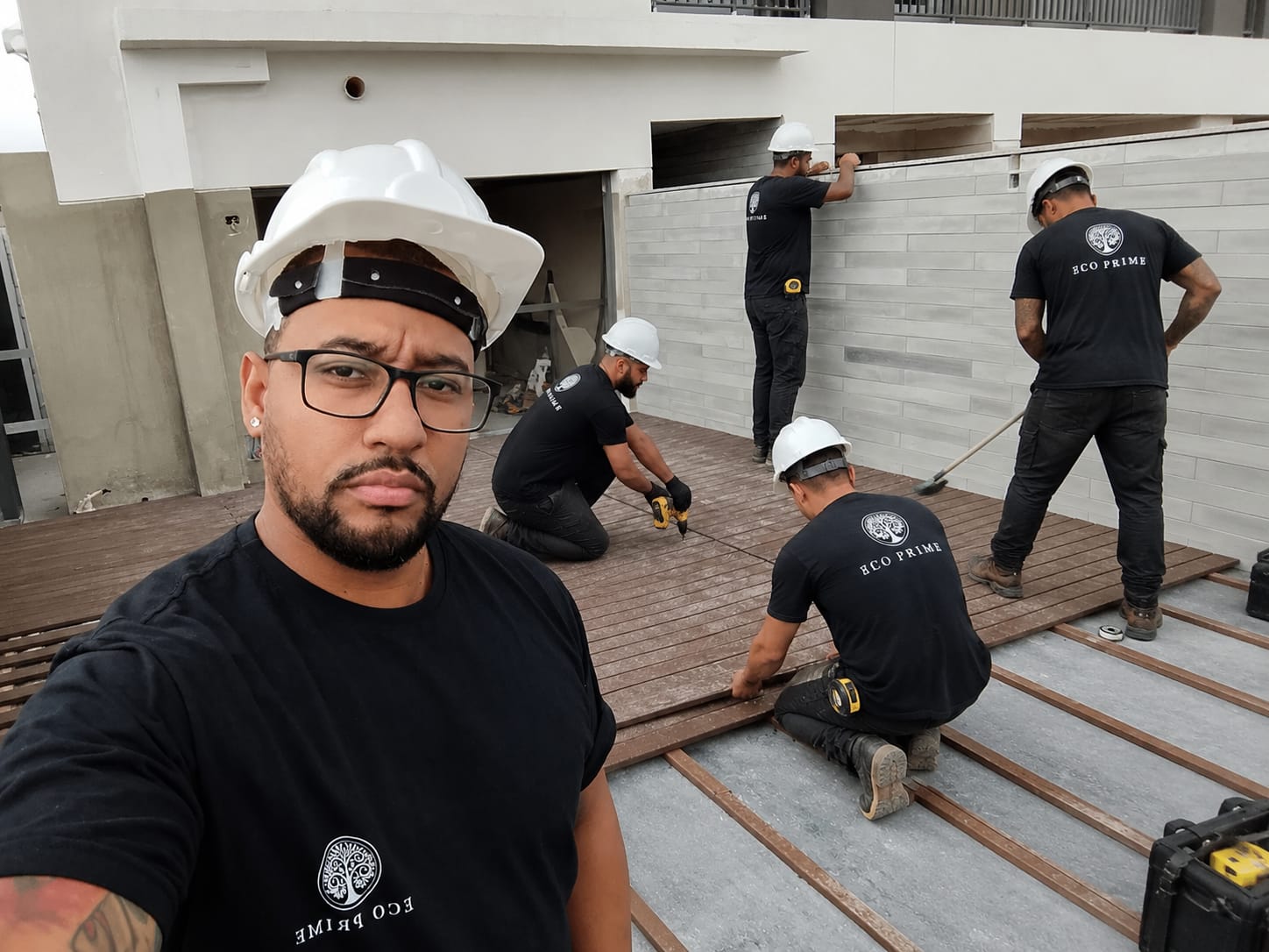 Equipe da Eco Prime instalando deck em obra, de capacete e camiseta da empresa